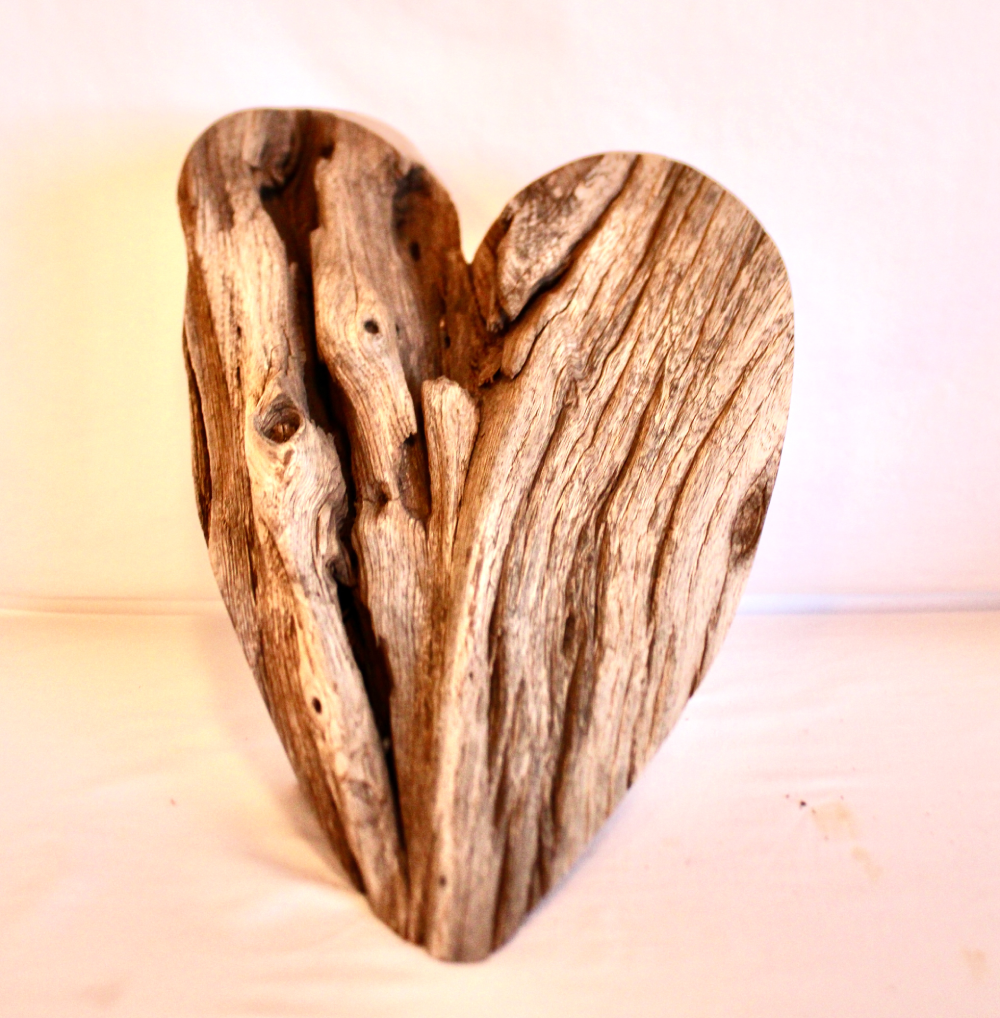 Heart-shaped driftwood sculpture on white background.